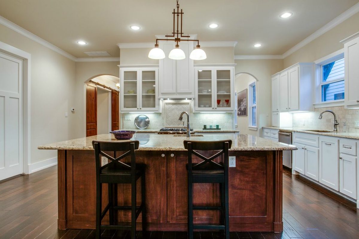 A remodeled kitchen with a walnut island and white perimeter cabinetry